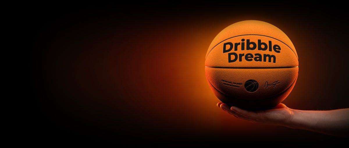 Hand holding the orange Dribble Dream silent basketball in an orange glow