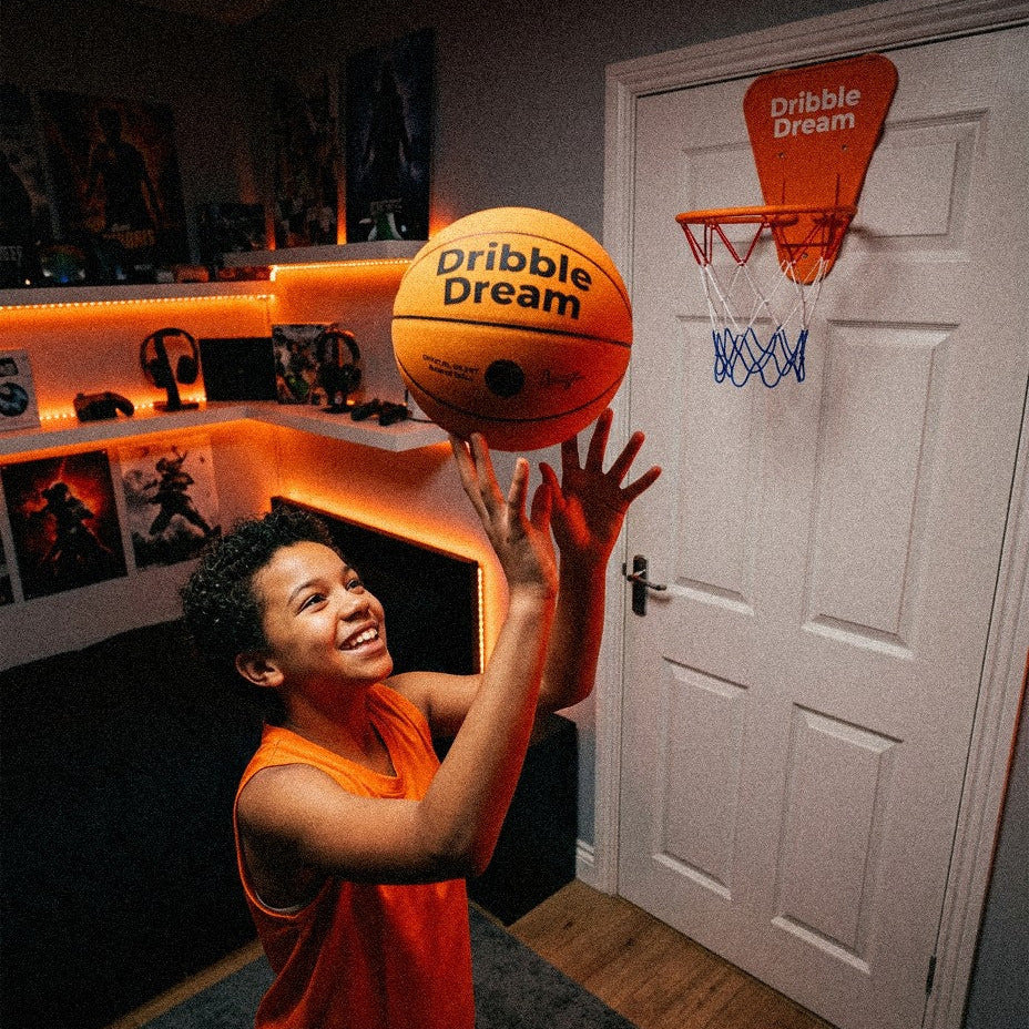 Boy shooting the Dribble Dream silent basketball at the mini hoop in his room